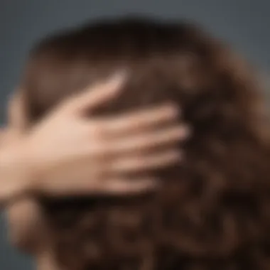 A close-up of a woman's hand applying leave-in conditioner to her thick, frizzy hair